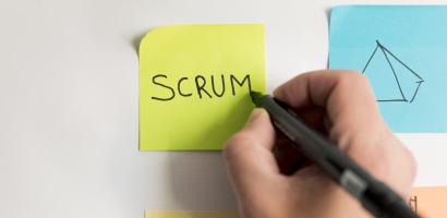 Hand writing "scrum" on post-it note