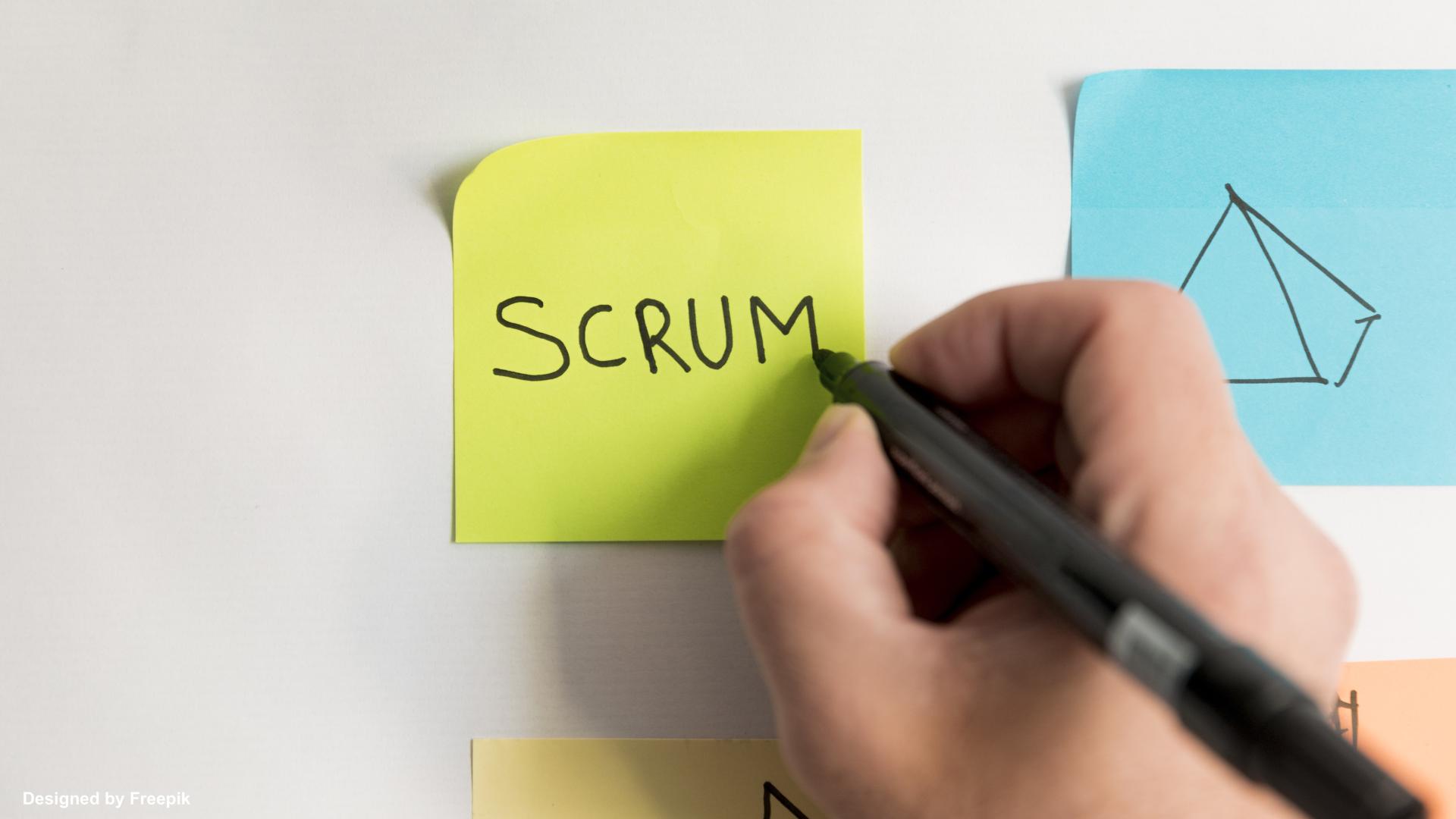 Hand writing "scrum" on post-it note